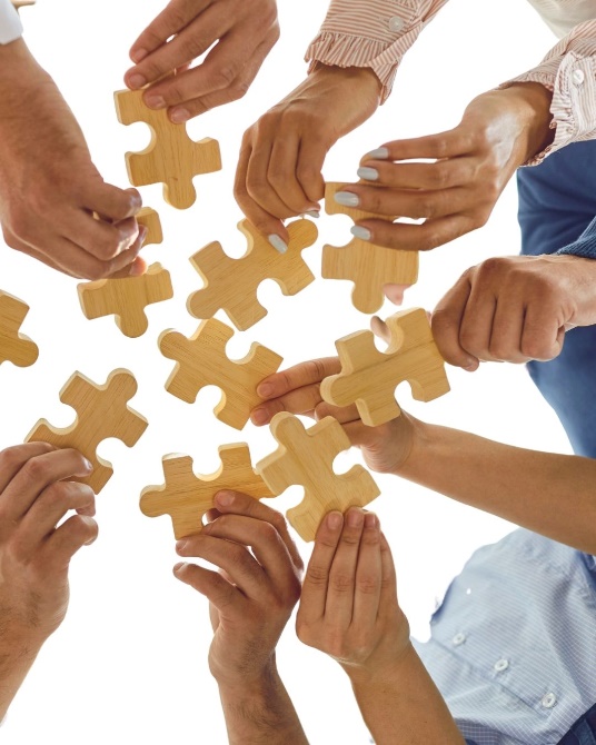 Birbirine uzanan ellerde birleşmeyi bekleyen ahşap puzzle parçaları